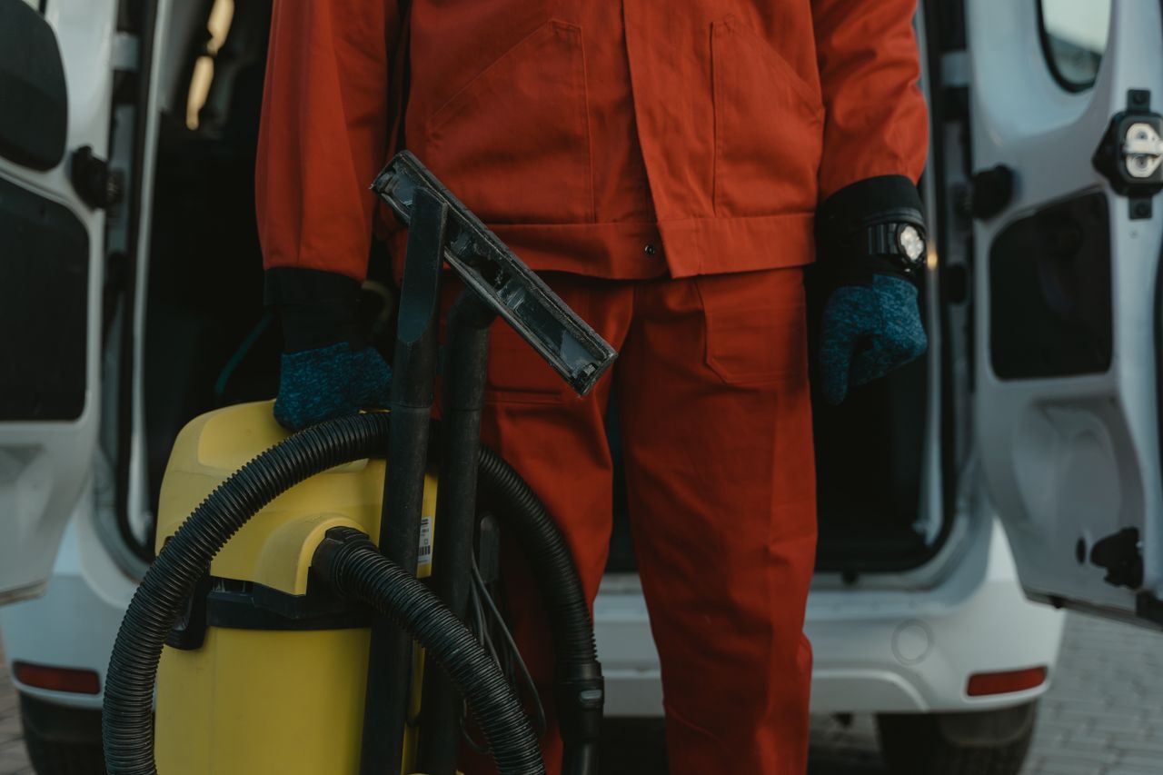 The Art of Drawing Readers In: Your attractive post title goes here A professional cleaner in a red uniform holding a vacuum near a van, ready for service.